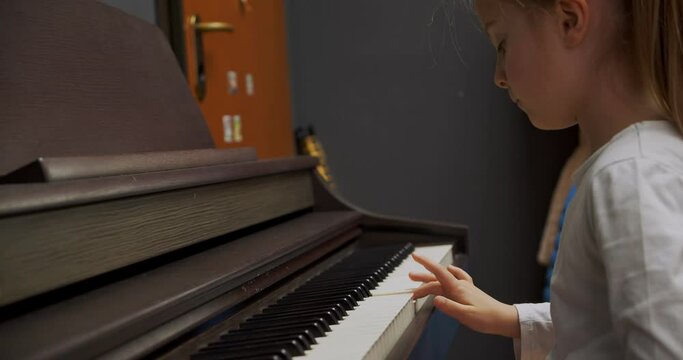 Little girl playing piano at home. Kid play piano in living room. Child learning piano at home. Music lesson, close up side view.