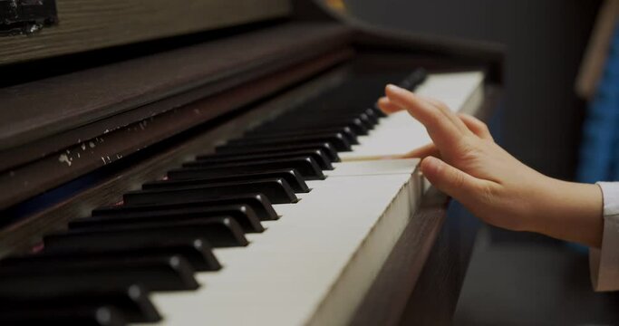 Little girl playing piano at home. Kid play piano in living room. Child learning piano at home. Music lesson, close up of hand, side view.