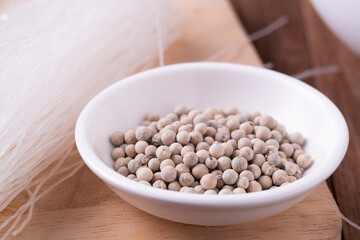 white Pepper seeds in white bowl on chopper board background