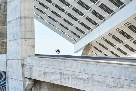 From below of anonymous person jumping or falling down from contemporary high rise concrete building