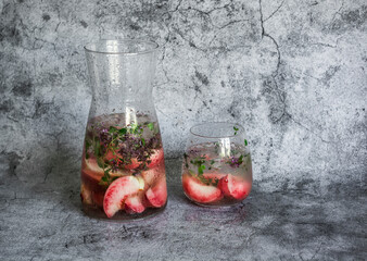Peaches, thyme summer refreshing lemonade cocktail on a gray background. Summer cold drink