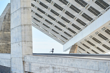 From below of anonymous person dancing on contemporary high rise concrete building