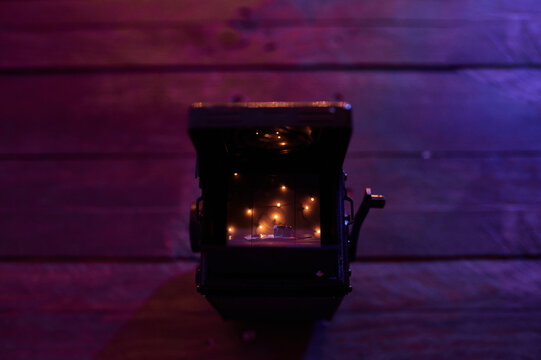 From above top view of retro photo camera wight lights of garland placed on wooden table in modern dark studio