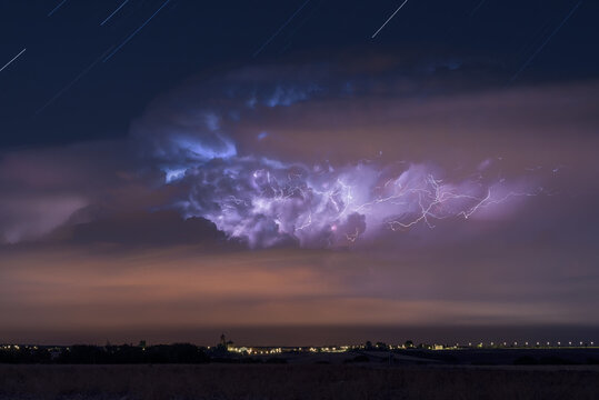 Dramatic Dark Stormy Sky With Glowing Lightnings Over Distant City At Night