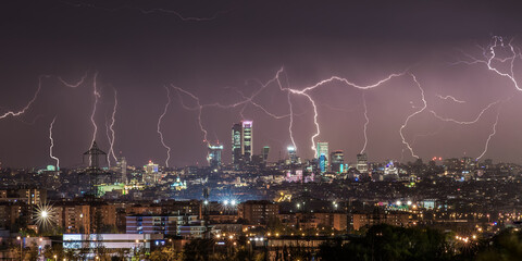 Amazing panoramic view of modern city with contemporary buildings and skyscrapers under dark night sky illuminated by plenty of lightnings