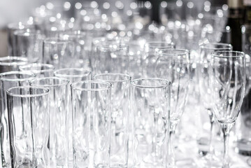 Lots of different empty glasses on the table. Preparing for a banquet, holiday or wedding. Blurred back.