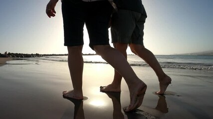 couple of two women walking together at the beach with barefoot enjoying their vacations and holiday outdoors having fun - people on the sand with water of the sea - caucasian person relaxing - Powered by Adobe