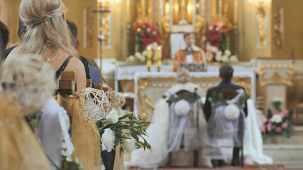 Guests sit on benches during a wedding in the Catholic Church.