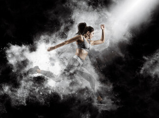 Obraz na płótnie Canvas Sporty young woman running on smoke background