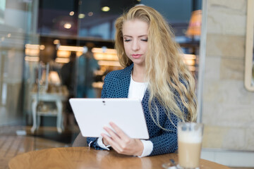 Young businesswoman on a coffee break. Using tablet computer.