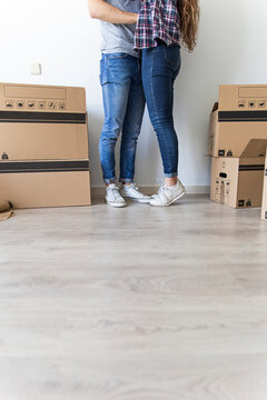 Crop view of couple in casual clothes hugging standing in room with carton boxes