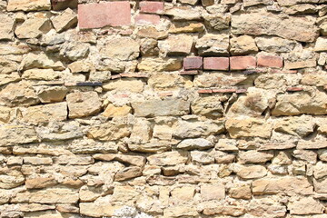 Alte Natursteinmauer historische Steinmauer,  gelb mit Gras und Blumen im Vordergrund