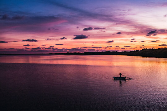 Silhouette of person rowing on boat while sailing in tranquil bay against marvellous sunset sky in Mexico