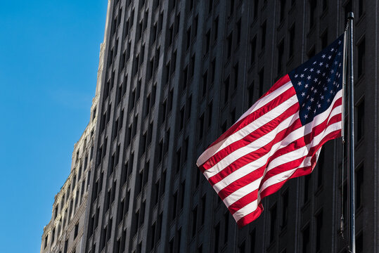 From below of vibrant national flag of USA hanging in row from stone building over street