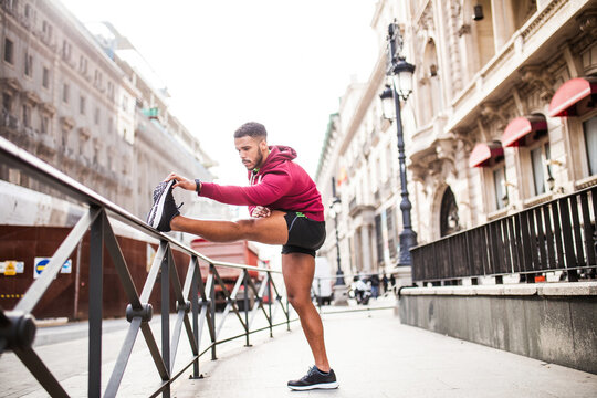 Young man stretching legs in the street