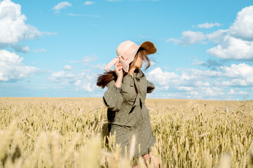 Stylish girl in dress and hat walking among herbs and wildflowers in field. woman smiling and relaxing in countryside, simple slow life style. freedom and hot summer. Atmospheric