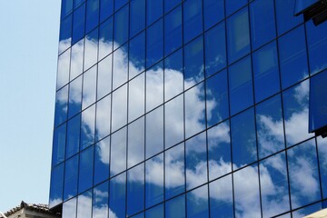 Fototapeta na wymiar Clouds reflected on glass windows of modern office building in the center of Athens in Greece, June 18 2020.