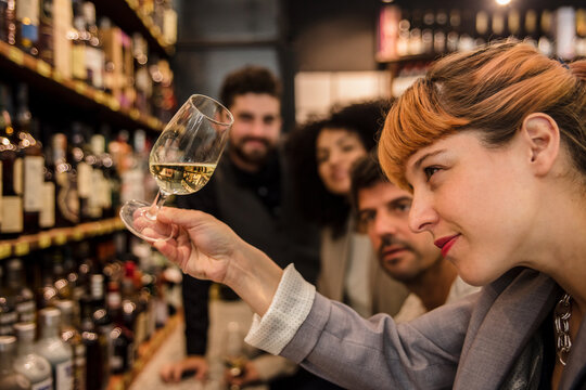 Group of people gathering in market wine house for tasting wine sorts and laughing happily.