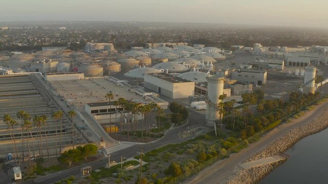 4k aerial parallax rotating view of a desalination plant near the coast of a beach.