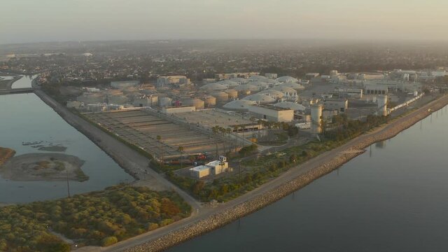 4k Aerial view glides high above a coastal desalinization plant.