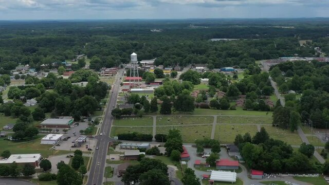 High altitude drone flyover of a small town area towards a silver water tower.