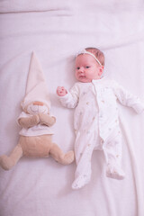 Portrait of sleeping one month old newborn baby girl laying with teddy bear. Flat lay composition. Cute baby girl on a light background in bed. At home.