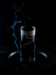 Brewing Chinese tea from a flower in a glass flask on a background of incense smoke