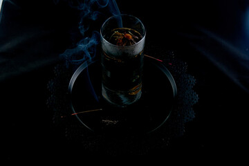 Brewing Chinese tea from a flower in a glass flask on a background of incense smoke