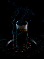 Brewing Chinese tea from a flower in a glass flask on a background of incense smoke