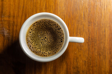 Xícara, isolada, de cerâmica com café sobre mesa de madeira.