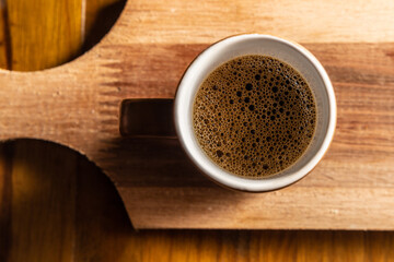 Xícara de cerâmica com café sobre uma mesa de madeira.