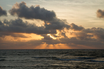 Dramatic sky and clouds. Seascape. The sea and ocean waves at sunrise. Beautiful daybreak orange, yellow and red colors.