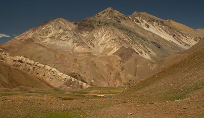 Alpine landscape. View of the mountain with sharp peaks, the meadow and valley in a sunny day.  