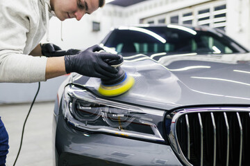 Car detailing - Worker with orbital polisher in auto repair shop.