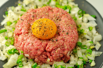 Beef steak tartare with raw egg yolk and onion with chive