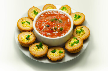 Mini scotch eggs with tomato sauce served on the white ceramic plate