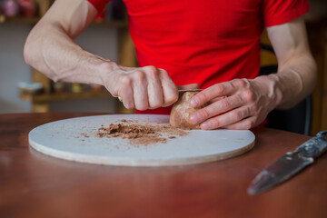 Professional male potter shaping and scraping dry clay cup with special tool in pottery workshop, studio. Crafting, artwork and handmade concept