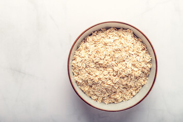 Gluten Free Rolled wholegrain oats or porridge oats in bowl, marble background, space for text