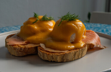 Delicious eggs Benedict with smoked salmon, hollandaise sauce and parsley.