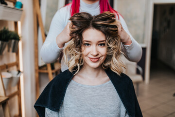 Beautiful hairstyle of young woman after dyeing hair and making highlights in hair salon.