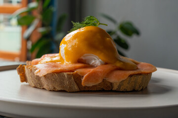 Delicious eggs Benedict with smoked salmon, hollandaise sauce and parsley.