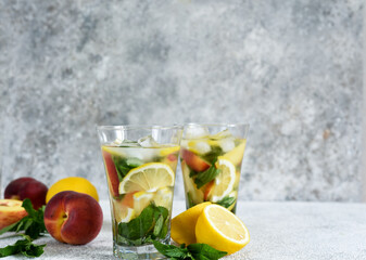 Lemonade with peach and mint in a glass cup on a concrete background. Peach lemonade.