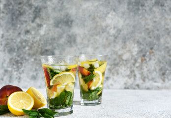 Lemonade with peach and mint in a glass cup on a concrete background. Peach lemonade.