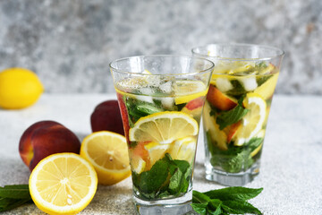 Lemonade with peach and mint in a glass cup on a concrete background. Peach lemonade.