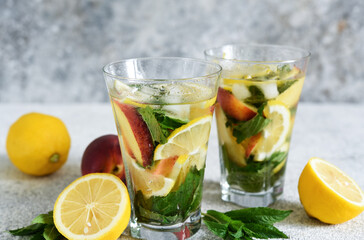 Lemonade with peach and mint in a glass cup on a concrete background. Peach lemonade.