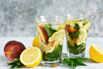 Lemonade with peach and mint in a glass cup on a concrete background. Peach lemonade.