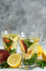 Lemonade with peach and mint in a glass cup on a concrete background. Peach lemonade.