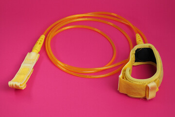 Yellow leash for surfboard on red background.