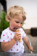 Little girl eating tube with whipped cream