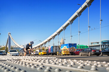 cars and a man in a helmet on a bicycle on the Crimean bridge in Moscow